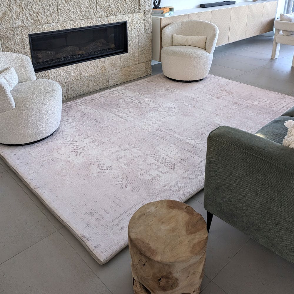 Modern living room with a textured rug, stone fireplace, and cozy rounded chairs.