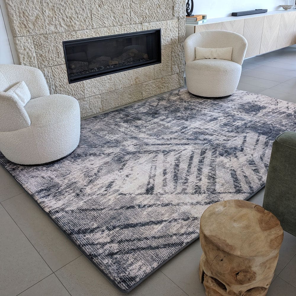 Modern living room with a textured rug, two white chairs, and a wooden accent table.