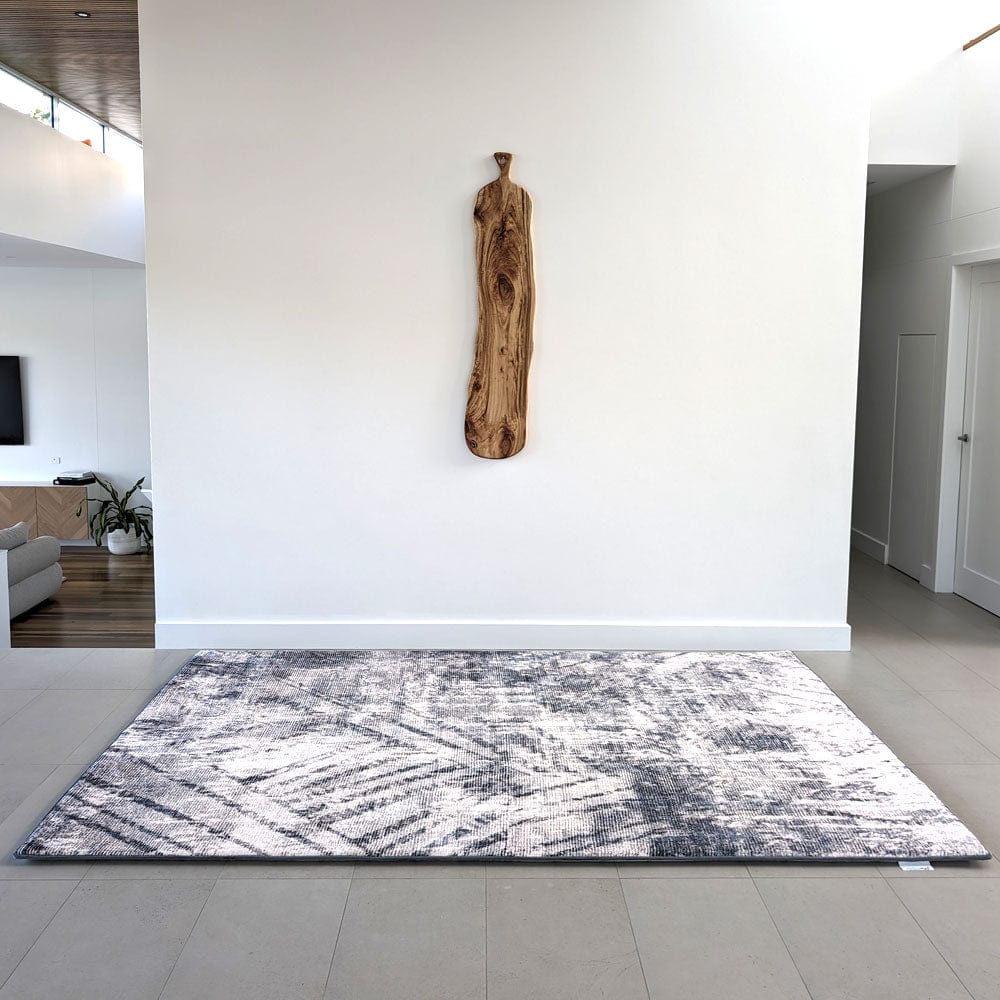 A modern room with abstract rug and wooden wall art.