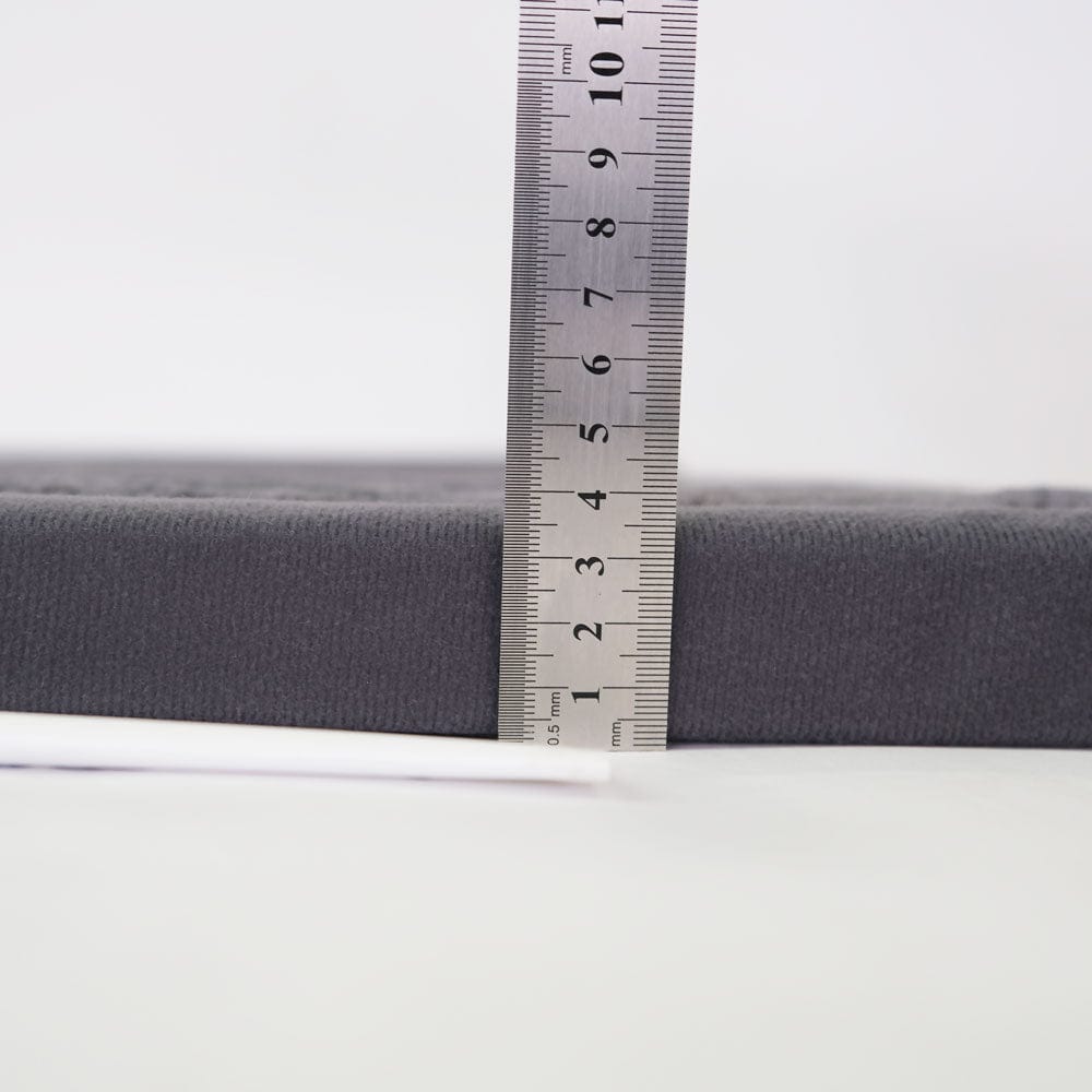 Close-up of a ruler measuring the thickness of a gray mattress.